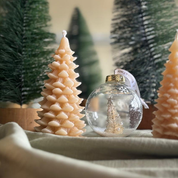 Decorative Christmas scene with small trees and ornaments on a table.